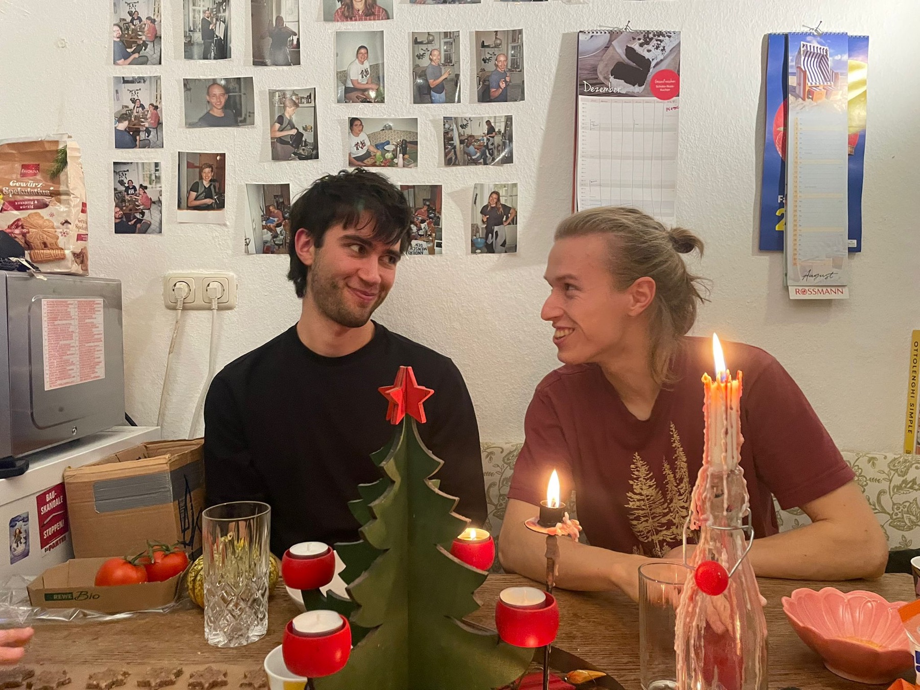 Niklas und Lennert am Küchentisch, Kerzen, Fotowand im Hintergrund