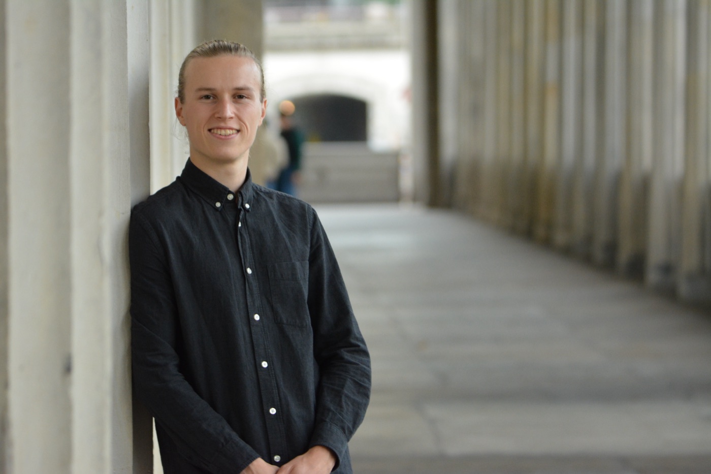 Niklas lehnt im Kolonnadengang an einer Säule